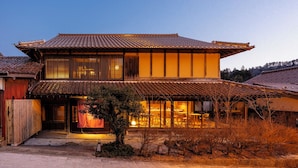 Una casa tradicional japonesa con techo de tejas, estructura de madera y un pequeño jardín delantero.