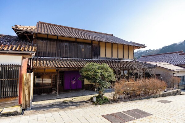 A traditional Japanese building with a tiled roof, wooden structure, and a purple entrance.