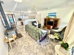 A living room with a sofa, a coffee table, a TV stand, and a dining area with a table and chairs. - 5 Rocks Off-Grid 4WD Retreat (Stockyard)