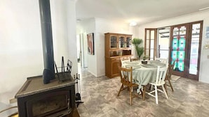 Un coin repas avec une table dressée pour quatre personnes, un buffet en bois et un po êle.