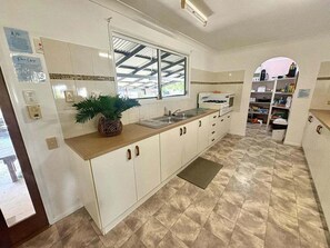 A kitchen with white cabinets, a sink, a window, and a potted plant. - 5 Rocks Off-Grid 4WD Retreat (Stockyard)
