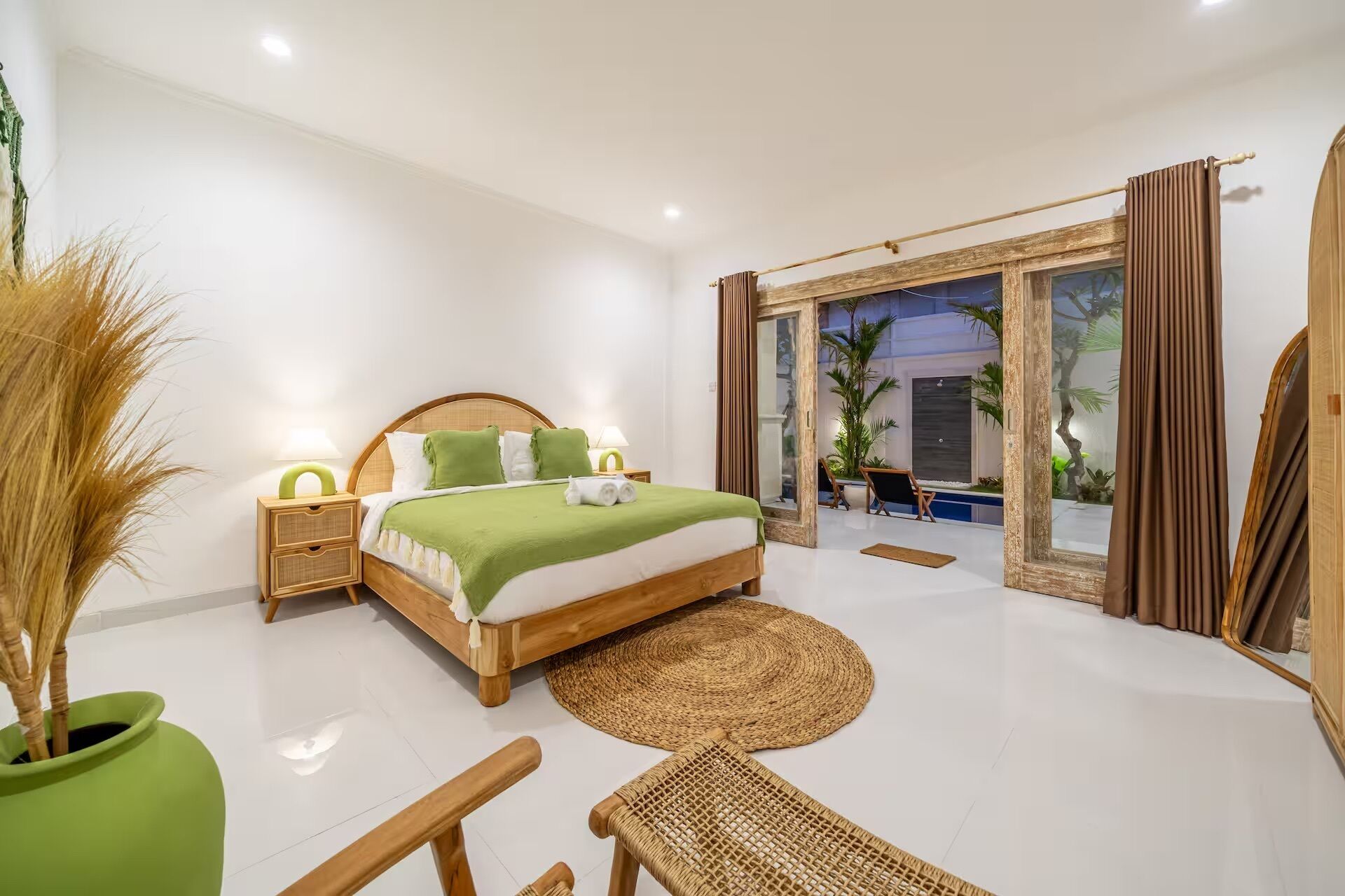 Een slaapkamer met een bed, nachtkastjes, een stoel, een grote spiegel en uitzicht.