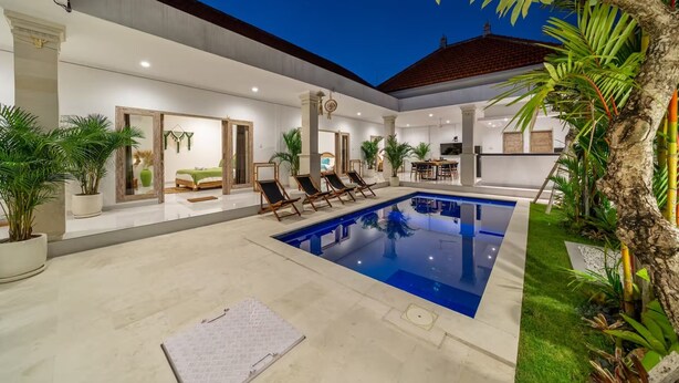 Uma casa moderna com piscina, área de estar externa e plantas tropicais.