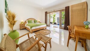 Quarto de hotel moderno com cama, mesa de jantar, cadeiras de vime e vista para o exterior.