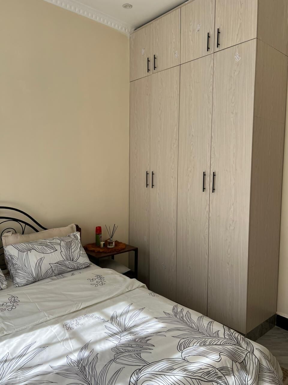 A bedroom with a bed, a nightstand, and a wardrobe.