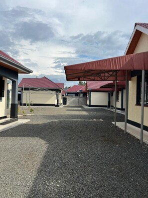 Um edifício com entrada por um caminho de cascalho e vagas de estacionamento cobertas.