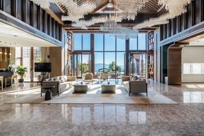 Eine geräumige Lobby mit hoher Decke, großen Fenstern und einem Kronleuchter.