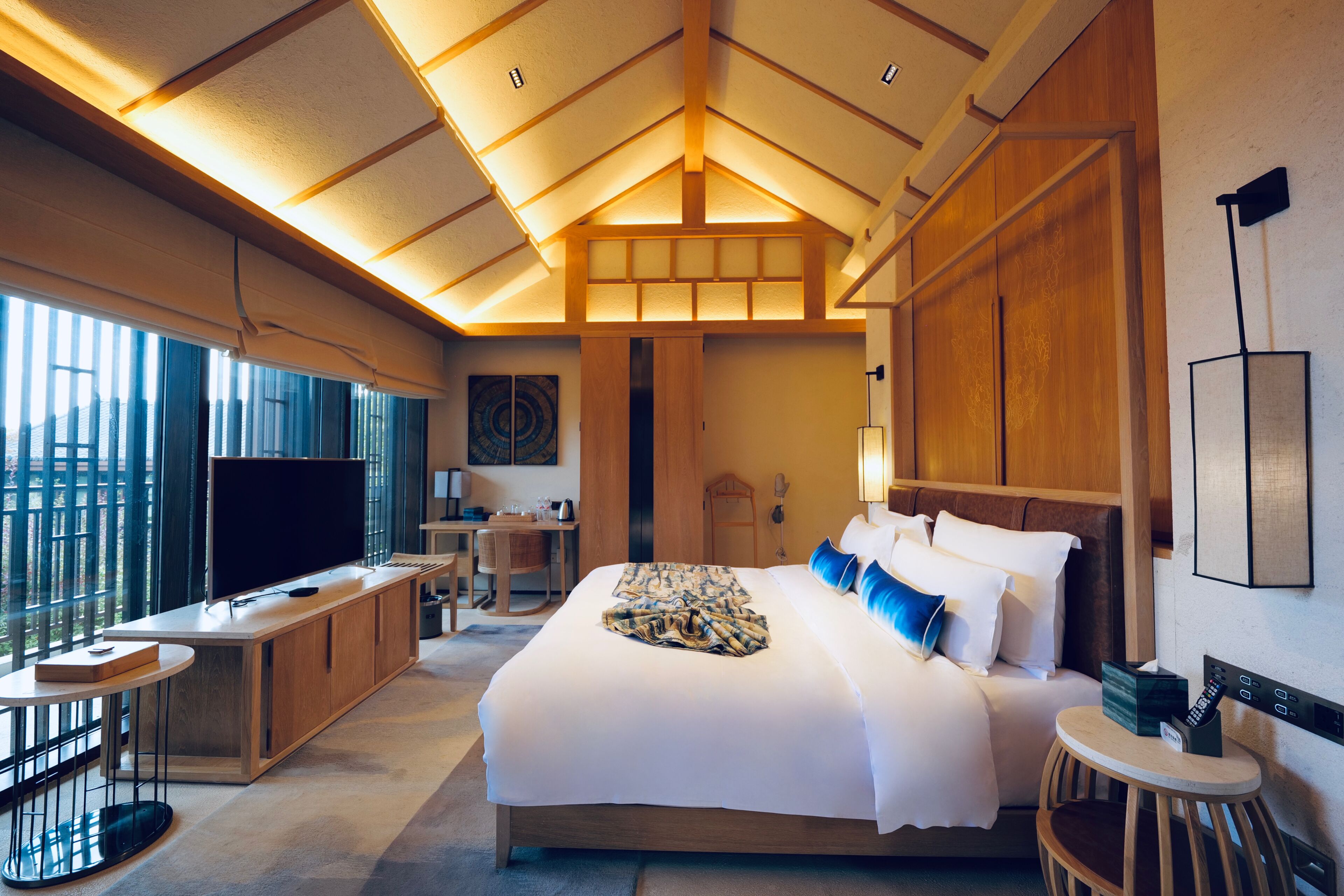 Ein modernes Hotelzimmer mit einem großen Bett, einem Schreibtisch, einem Fernseher und Balkonblick.