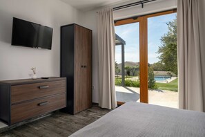 A bedroom with a bed, a TV, a wardrobe, and a sliding glass door to a pool area.