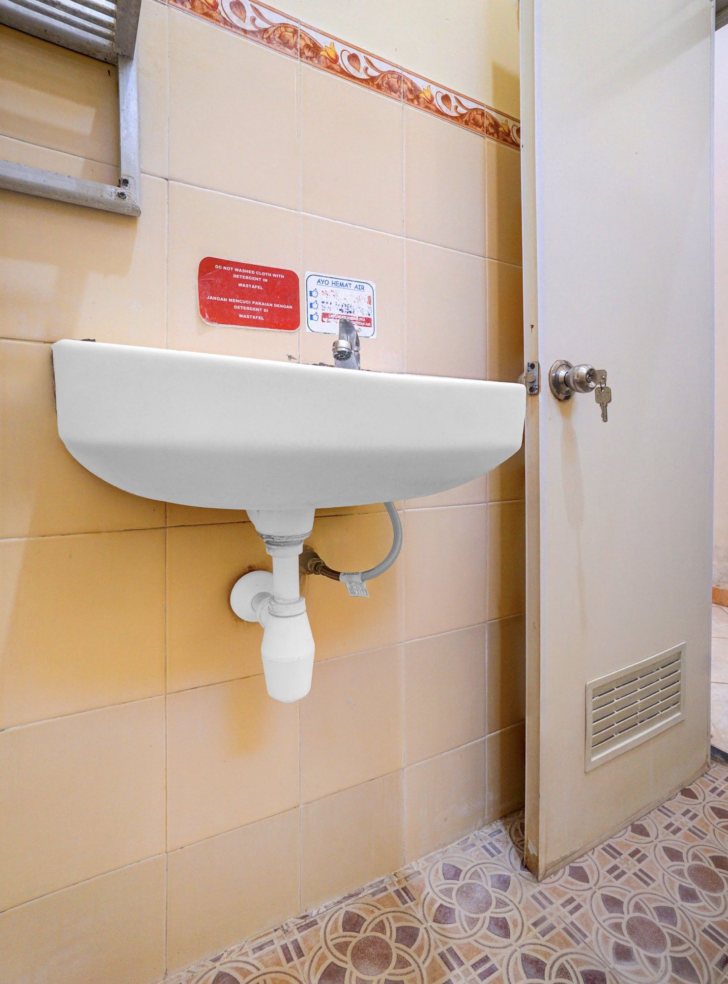 A bathroom with a white sink, a red warning sign, and a door with a keyhole.