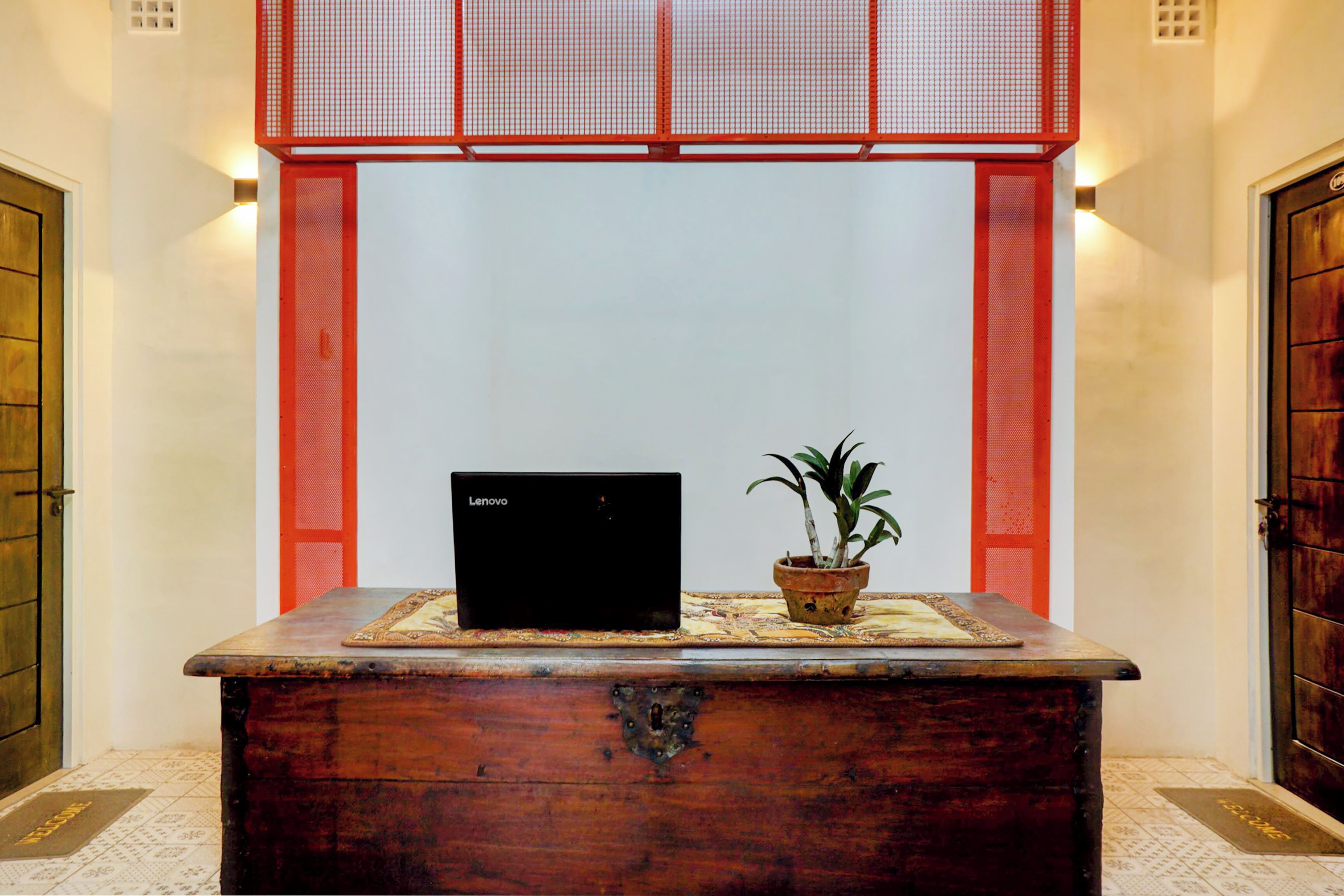 Un mostrador de recepción de madera con una computadora portátil y una planta en maceta.