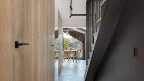 A modern interior with a wooden door, a staircase, and a view of a dining area with a table and chairs. - Luxury Apartment in Szczyrk | Mountain Views, Air Conditioning (Szczyrk)