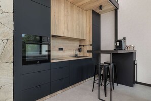 Eine moderne Küche mit schwarzen Schränken, einer Holzarbeitsplatte, einem eingebauten Backofen und einer Kaffeemaschine.
