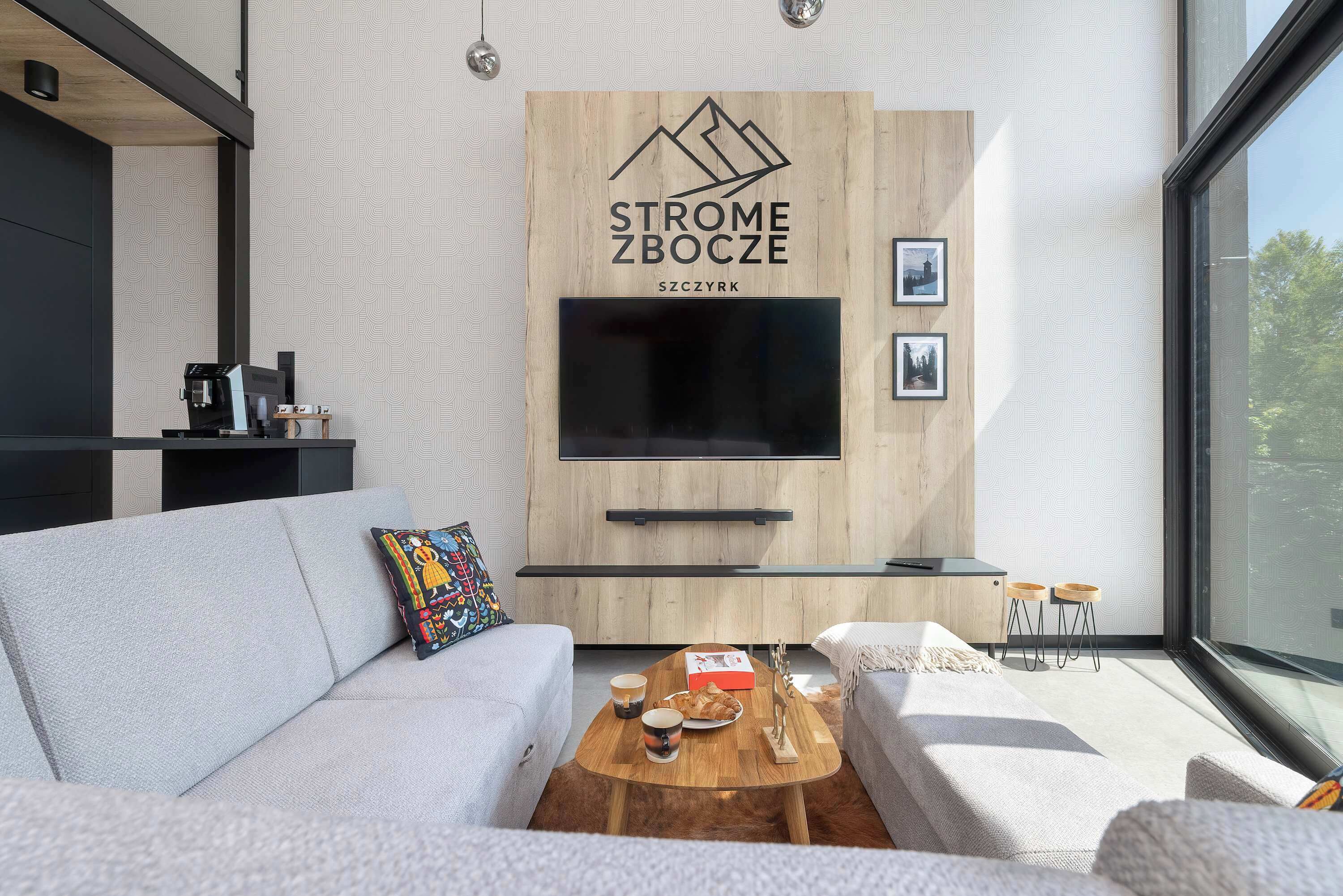Un salon moderne avec un canapé, une table basse et un téléviseur fixé au mur.