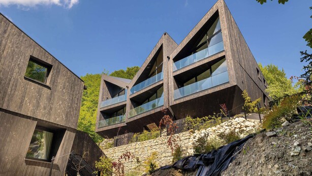 A modern building with a unique triangular design, large windows, and a stone base. - Luxury Apartment in Szczyrk | Mountain Views, Air Conditioning (Szczyrk)