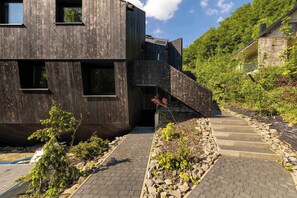 Ein modernes Gebäude mit Holzfassade, Steinstufen und einem Gartenbereich.