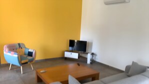 A living room with a sofa, a coffee table, a colorful armchair, a TV, and a white cabinet. - Beautiful, comfortable villa (Prunelli-di-Fiumorbo)