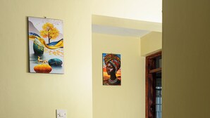 Ein Flur mit zwei Bildern, einem Lichtschalter und einer Tür zu einem weiteren Raum.