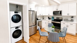 A modern kitchen with white cabinets, stainless steel appliances, and a dining area with a glass table and chairs. - Private 1BR Apt, 2BD 1BA, Sleeps 5, Clean & Reliable, Near NYC (Scotch Plains)