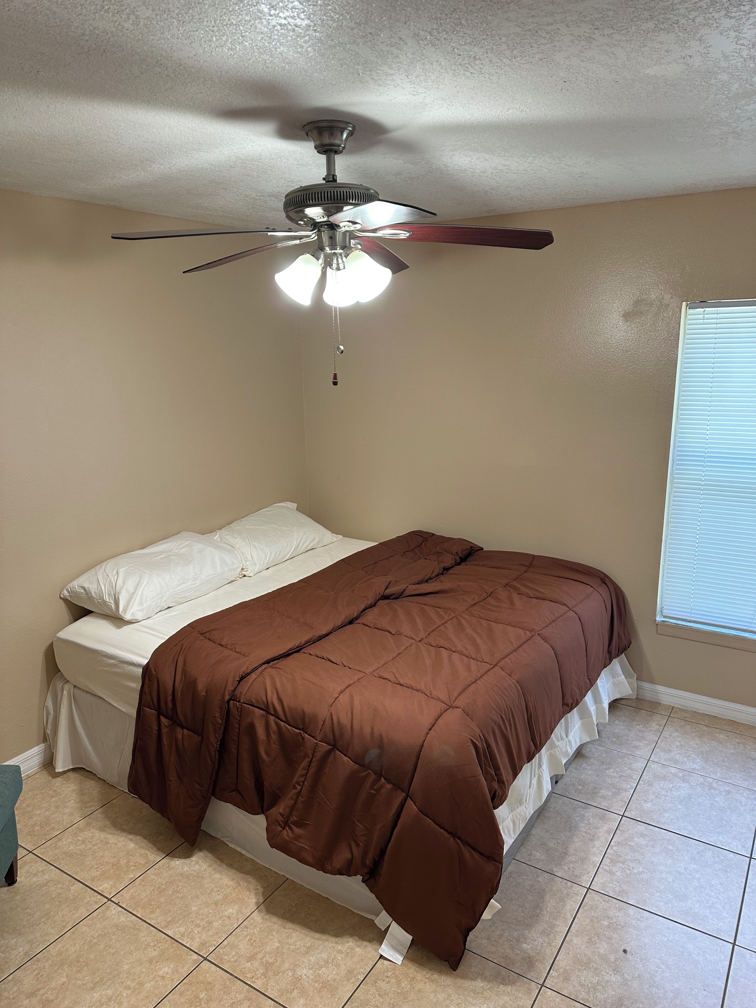 Une chambre à coucher avec un lit, un ventilateur de plafond et une fenêtre.