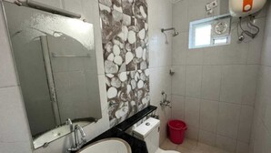 Une salle de bain équipée d’un lavabo, de toilettes, d’un miroir et d’une douche.