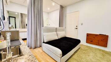 A modern bedroom with a bed, a sink, a mirror, and a wooden panel on the wall.