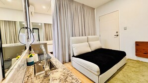 A modern bedroom with a bed, a built-in desk, a mirror, and a window with curtains.