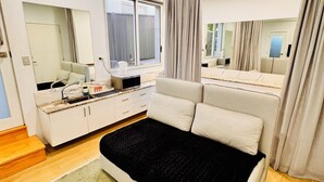 A modern bedroom with a bed, a dresser, a mirror, and a window.