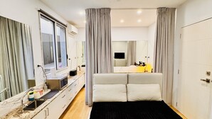 A modern bedroom with a large bed, a built-in desk, and a television.