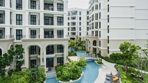 A multi-story hotel with balconies, a swimming pool, and lush greenery. - Charming balcony studio in Title Legend (Choeng Thale)