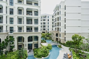 Ein mehrstöckiges Hotel mit Balkonen, einem Schwimmbad und üppigem Grün.