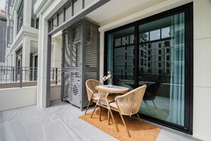 Ein Balkon mit rundem Tisch und Stühlen, einer Glastür und Blick auf Gebäude.