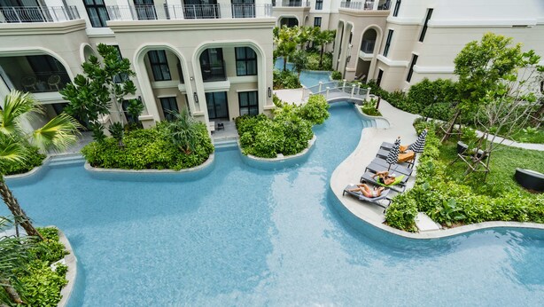 A multi-level hotel with a central swimming pool, outdoor seating areas, and lush landscaping. - Charming balcony studio in Title Legend (Choeng Thale)