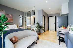 A modern bedroom with a bed, a desk, and a potted plant. - Charming balcony studio in Title Legend (Choeng Thale)