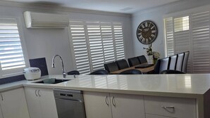 Uma cozinha moderna com máquina de lavar louça, pia e um relógio grande na parede.