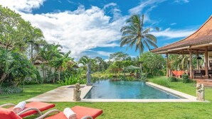 A pool with lounge chairs, a covered seating area, and tropical vegetation. - Bali Sawah Indah  (Tampaksiring)