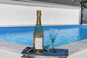 A bottle of wine and a glass on a tray by a pool. - Villa Emma by Istrabook (Pula)