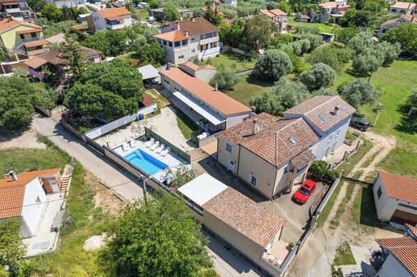 An aerial view of a residential area with houses, a swimming pool, and a red car parked on the street. - Villa Emma by Istrabook (Pula)