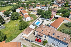 An aerial view of a residential area with houses, a swimming pool, and a red car parked in front of a house. - Villa Emma by Istrabook (Pula)
