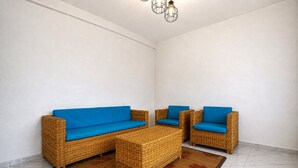Una habitación con un conjunto de sofá y sillones de mimbre, y un reposapiés a juego.