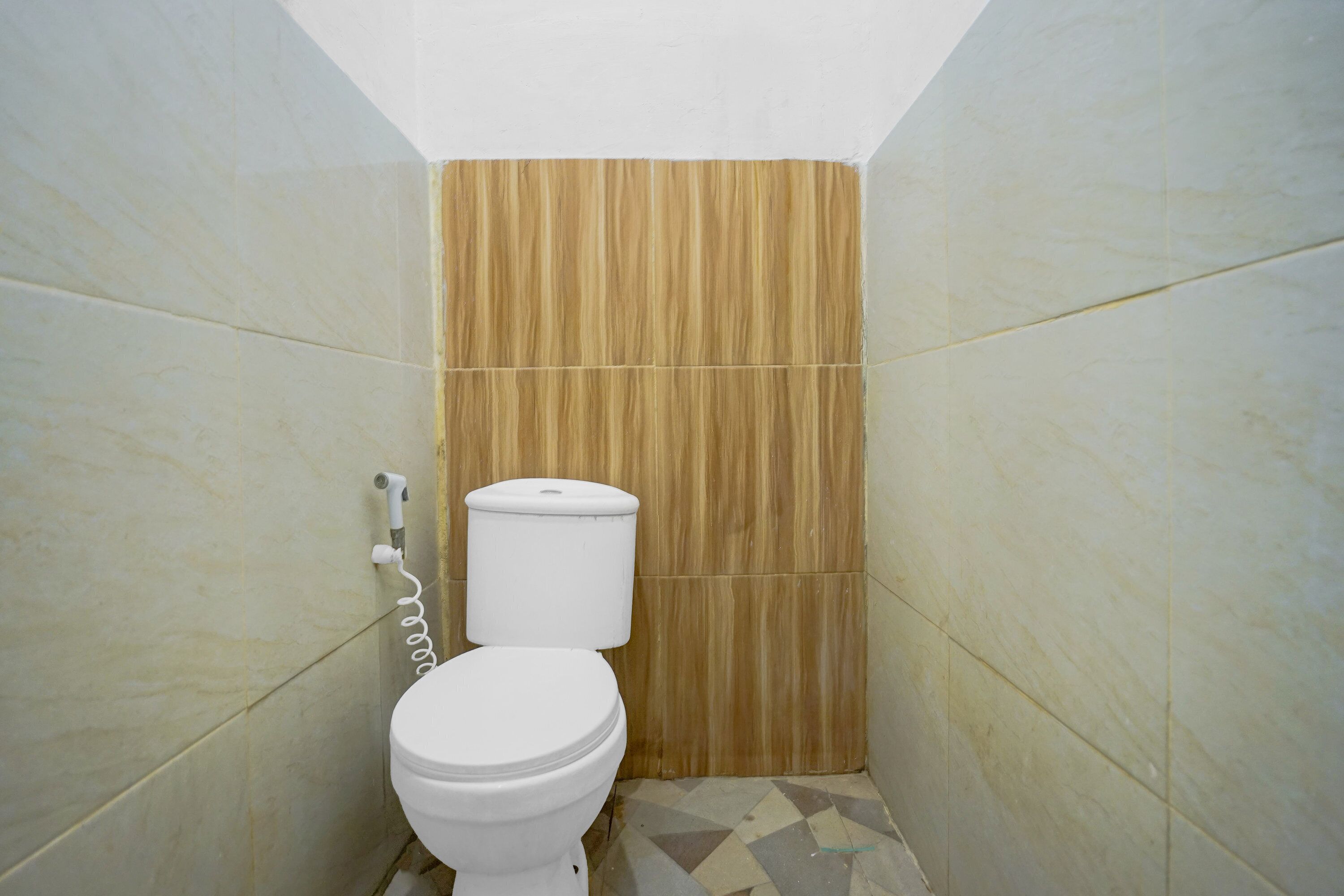 A small bathroom with a toilet and a shower head on the wall.