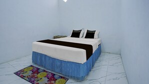 Un dormitorio con cama, mesita de noche, ventana y alfombra con estampado floral.