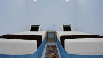A room with two beds, a small table, and a colorful floral carpet.