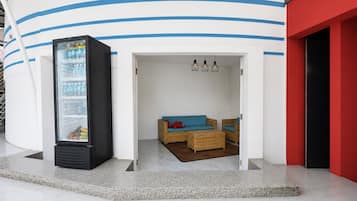 A modern interior with a seating area, a refrigerator, and a red wall.
