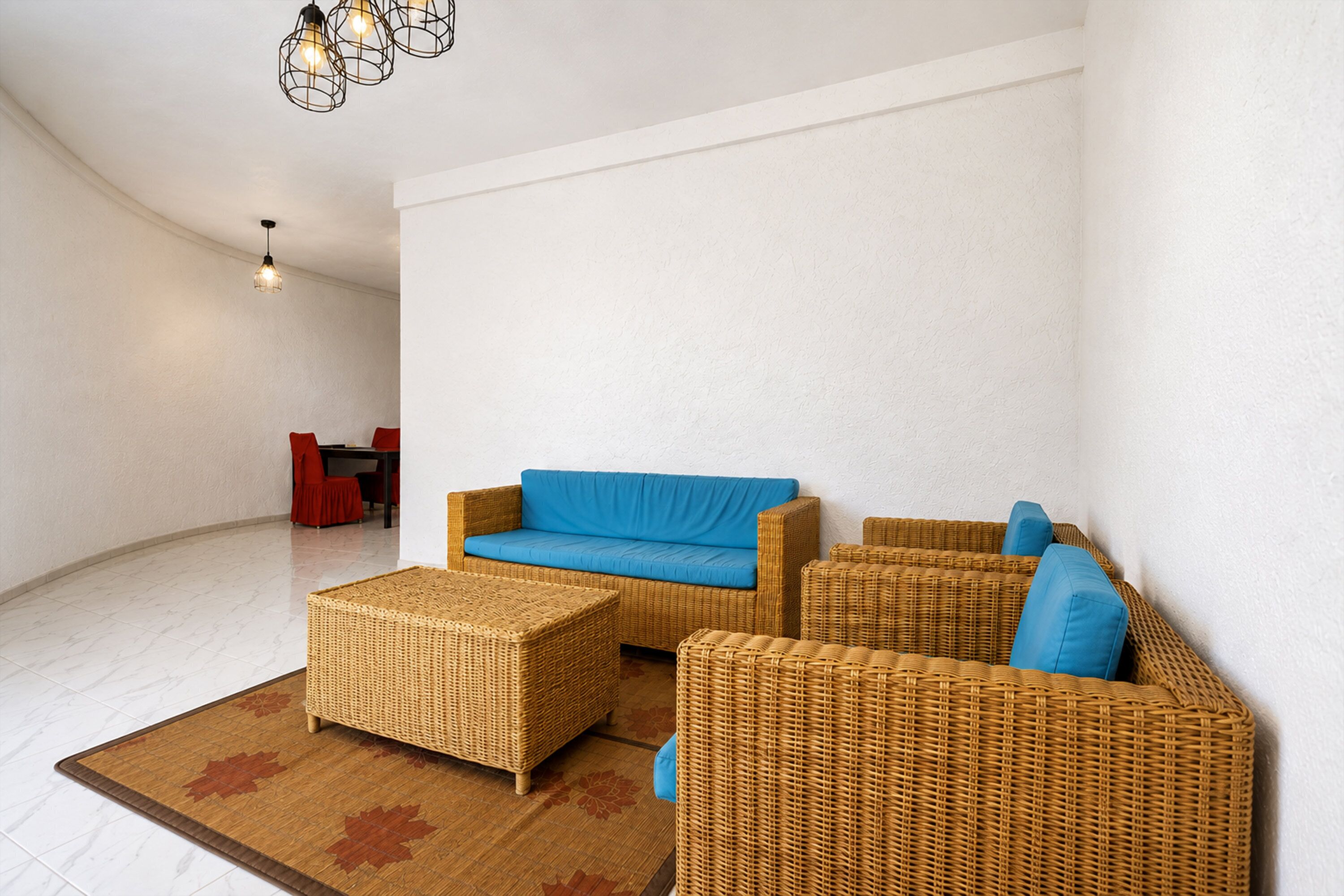 A spacious living area with a blue sofa, wicker furniture, and a patterned rug.