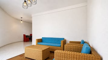 A spacious living area with a blue sofa, wicker furniture, and a patterned rug.