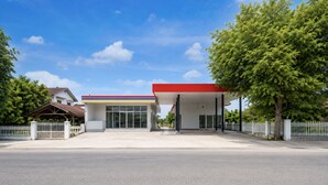 Una estación de servicio con techo rojo, paredes blancas y una franja azul y amarilla.