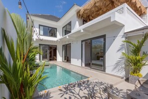 A modern house with a swimming pool, large windows, and a thatched roof. - Siddhi Villa (Kerobokan)