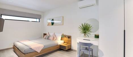 Un dormitorio moderno con cama, mesita de noche, escritorio, silla y una planta en maceta.