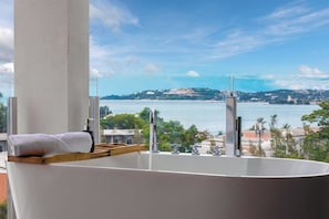 Una bañera con vistas a un cuerpo de agua y un paisaje distante.